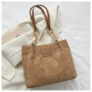Detailed macro of khaki corduroy tote bag with fashion label and gold chain link