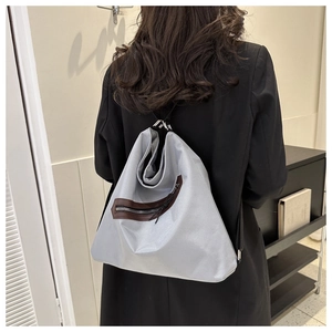 Detail of light grey minimalist backpack with brown leather trim and metallic luster