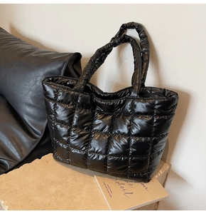 Detailed view of black glossy quilted tote bag with padded handles and square patterns