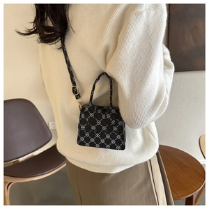 Detail view of mini black crossbody bag with white geometric patterns on a fashion model