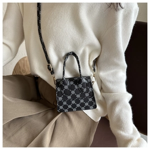 Detailed macro of a black mini crossbody bag featuring a white geometric chain pattern