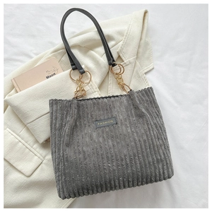 Detail of grey corduroy tote bag showing gold chain strap and FASHION patch logo