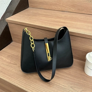 Minimalist black PU leather shoulder bag with golden chain and metallic buckle on wooden steps