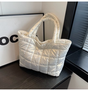 Detail of white quilted puffy tote bag with glossy finish and square padded texture