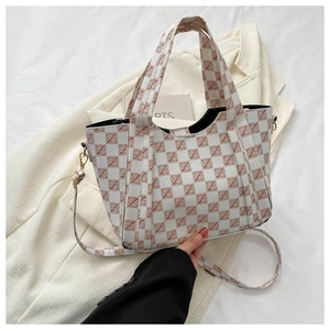 Detail of checkered pattern on crossbody bag with handle and shoulder strap