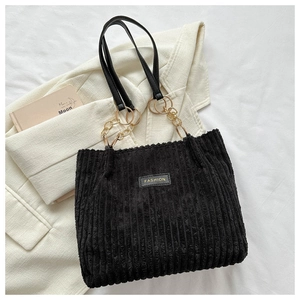 Detail of black corduroy tote bag with fashion leather patch and gold chain strap