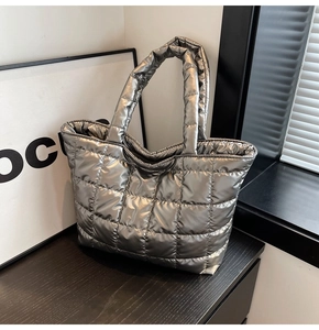 Detail of silver metallic quilted tote bag with padded texture and glossy stitching finish