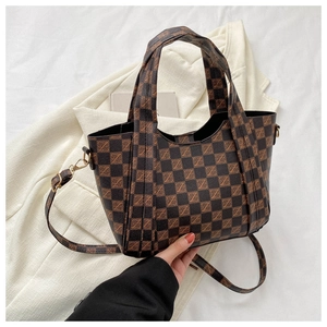 Close-up of checkered monogram tote bag showing leather texture and gold buckle detail