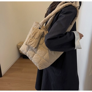 Detail of beige quilted shoulder bag with puffy star stitching and a matching small pouch