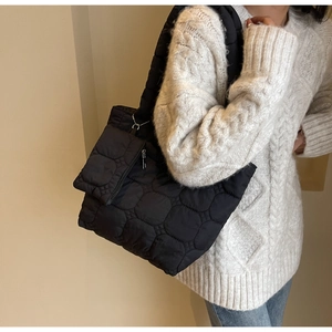 Detail of black quilted tote bag with matching detachable pouch and silver chain