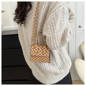 Detailed side view of khaki PU mini crossbody bag with black geometric pattern on a model