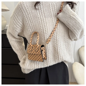 Detailed view of a vintage mini crossbody bag with khaki geometric patterns on a beige sweater