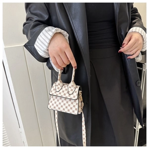 Detail of a mini crossbody bag featuring brown geometric patterns and gold hardware