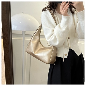Mirror selfie showing a champagne gold pleated hobo bag with a scrunched shoulder strap