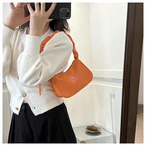 Détail du sac porté épaule orange avec broderie papillon et bandoulière froncée