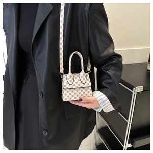 Detailed view of a mini monogram shoulder bag on a black leather jacket with natural lighting