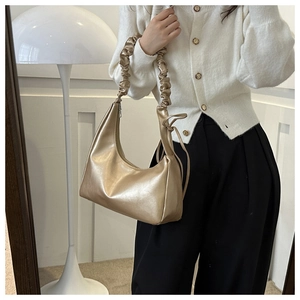 Detail of champagne gold hobo bag featuring pleated handle and metallic faux leather texture
