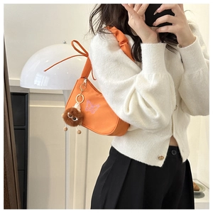 Détail du sac hobo orange avec broderie papillon rose et breloque peluche rigolote