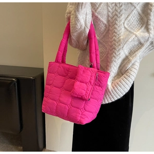 Detail of rose pink quilted nylon tote bag with matching mini pouch on model side