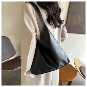 Detail of large black tote bag showing smooth PU leather texture and shoulder strap fit