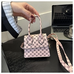 Mini pink crossbody bag with vintage clover pattern held by hand in office setting