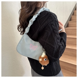 Détail du sac bandoulière bleu clair avec broderie papillon rose et bandoulière froncée