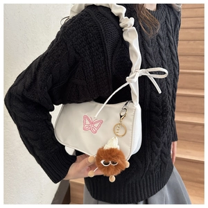 Détail du sac à bandoulière blanc avec broderie papillon rose et bandoulière plissée avec bijou