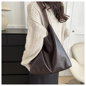 Detail of a soft dark brown leather tote bag showing high-quality texture and wide strap