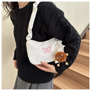 Détail du sac blanc avec broderie papillon rose et breloque en peluche marron