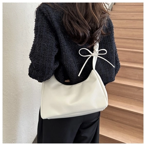 Detail of cream white pleated cloud bag showing side bow accent and soft PU leather texture
