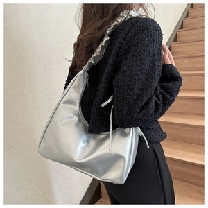 Silver metallic dumpling bag with ruffled shoulder strap worn as an underarm bag