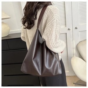 Detail of dark brown leather tote bag showing smooth texture and large capacity design