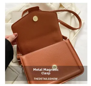 Detail of brown litchi pattern leather bag with golden magnetic snap closure