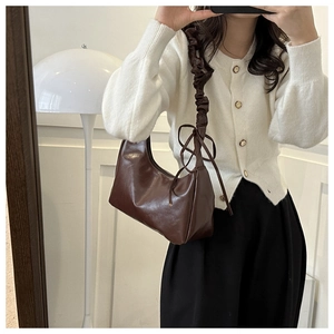 Detailed view of dark brown cloud bag with scrunchie strap and bow detail for women