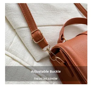 Close-up of brown litchi texture leather bag with adjustable golden metal buckle details