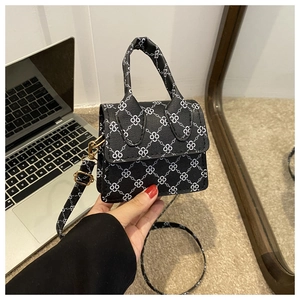 Detail of black mini handbag with white floral lattice pattern and top handle