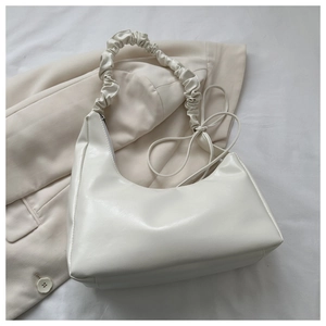 Macro shot of white minimalist hobo bag featuring glossy faux leather and scrunchie strap