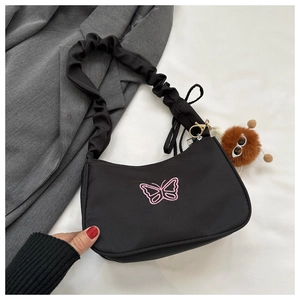 Détail du sac bandoulière en nylon noir avec broderie papillon et bandoulière froncée