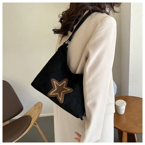 Détail d'un sac porté épaule vintage en daim noir avec un patch étoile dorée pailletée