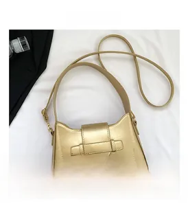 Close-up of golden metallic shoulder bag with magnetic flap and embossed logo detail