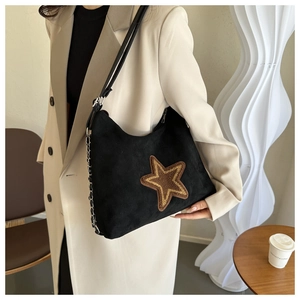 Detail shot of the large star patch and metal chain strap on the black suede shoulder bag