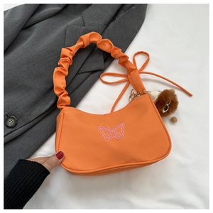 Détail du sac orange avec broderie papillon rose et pendentif d'ours en peluche mignon