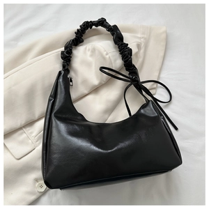 Close-up of black PU leather hobo bag with pleated shoulder strap and delicate side bow tie