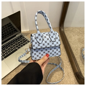 Detail of light blue mini handbag with black clover pattern and detachable strap