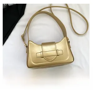 Metallic champagne gold shoulder bag detail showing brand logo and compact size