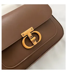 Gros plan d'un sac à bandoulière en cuir marron avec fermoir tournant en métal doré vintage