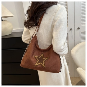 Close-up of brown suede hobo bag featuring a gold star patch and chain strap detail