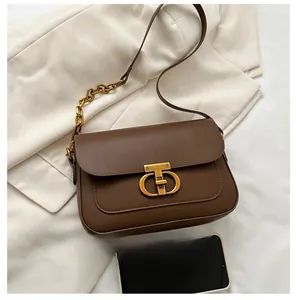 Détail d'un sac à bandoulière en cuir marron avec fermoir CD doré et bandoulière en chaîne