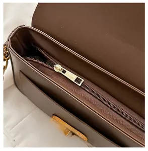 Détail de la fermeture éclair dorée et des coutures sur le sac bandoulière en cuir marron