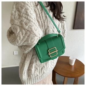 Detail of bright green pebble leather handbag with gold buckle shown on a model